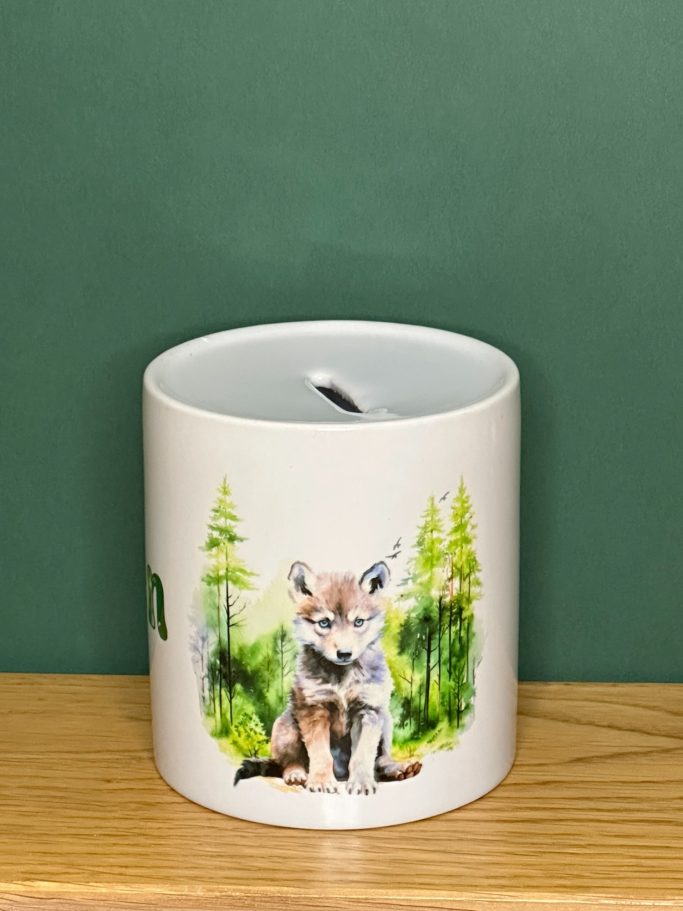 Spardose Wolf-Motiv Spardose aus Keramik mit Wolf vor Wald Motiv. Schlitz in Oberseite, in Unterseite Loch mit Kunststoffdeckel zum Verschließen der Spardose.